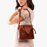 Nutmeg Small | Model holding symmetrical leather bag with leather drawstring closure and adjustable shoulder strap