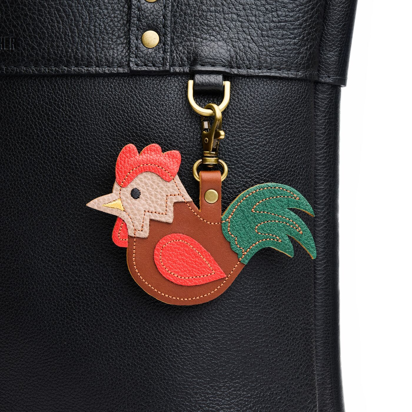 Hank | A rooster-shaped keychain hanging on a pebbled black bag