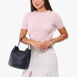 Night Owl Large | Model carrying symmetrical bucket bag with handle, latch closure, and removable crossbody strap