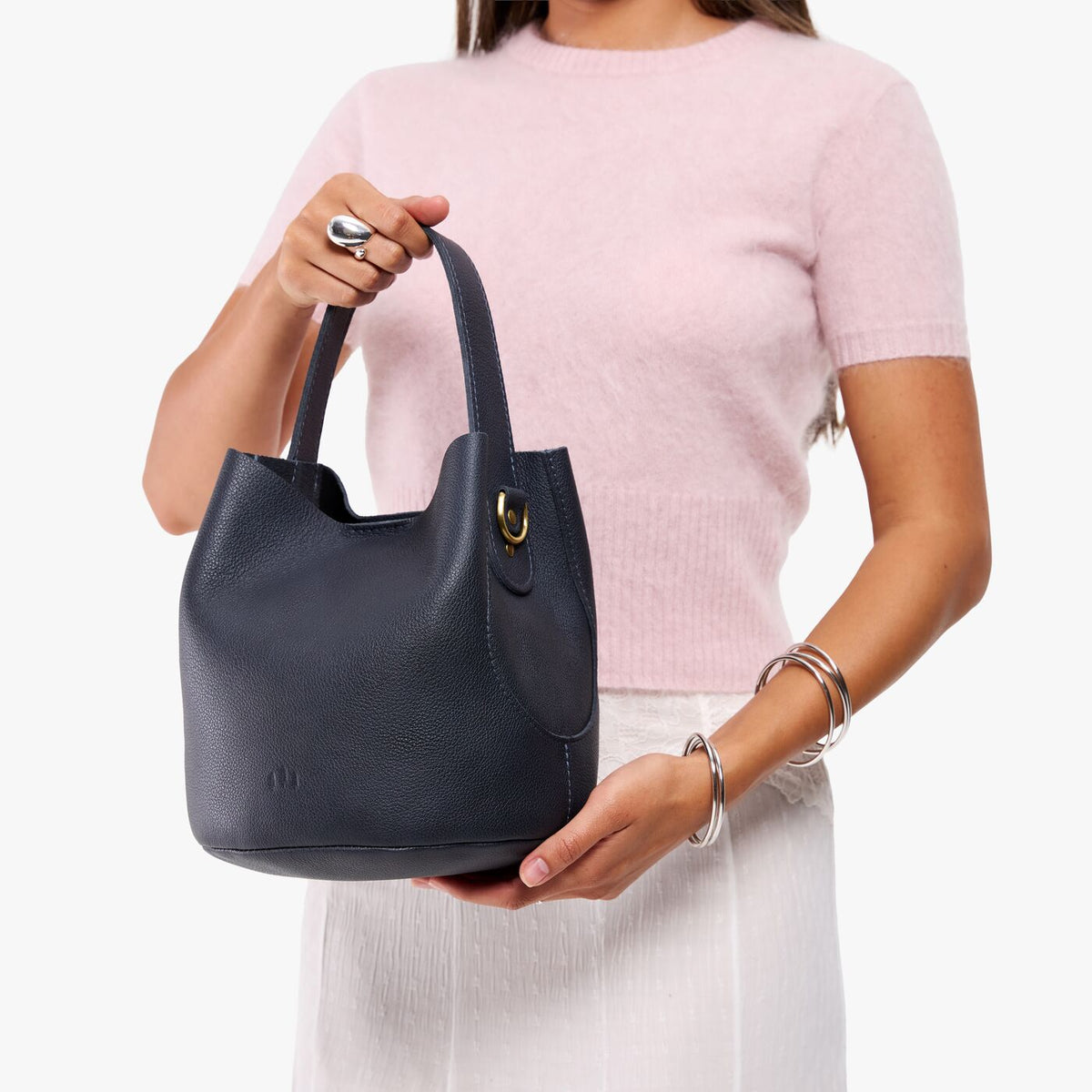 Night Owl*Large | Model carrying symmetrical bucket bag with handle, latch closure, and removable crossbody strap