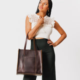 Grizzly North/South | Model holding structured large tote bag with overlapping panels and crossbody strap