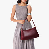 Cabernet Large | Model holding a bean shaped shoulder bag with a zipper closure
