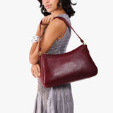 Cabernet Large | Model holding a bean shaped shoulder bag with a zipper closure