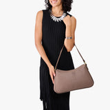 Sparrow Large | Model holding a bean shaped shoulder bag with a zipper closure