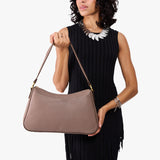 Sparrow Large | Model holding a bean shaped shoulder bag with a zipper closure