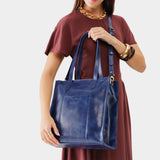 Cowboy Blue North/South | Model wearing structured large tote bag with overlapping panels and crossbody strap
