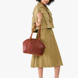 Nutmeg Large | Model holding a half circle crossbody bag with handles and removable crossbody strap 