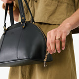 Black Small | Model holding a half circle crossbody bag with handles and removable crossbody strap 