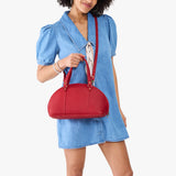 Cherry Small | Model holding a half circle crossbody bag with handles and removable crossbody strap 
