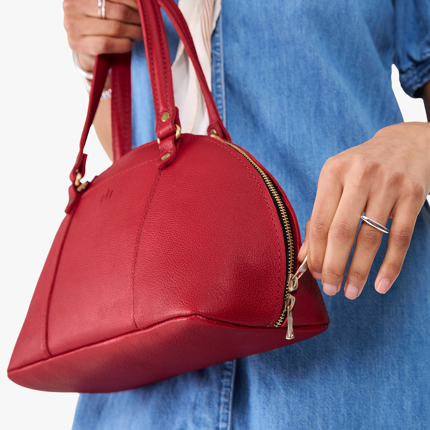 Cherry*Small | Model holding a half circle crossbody bag with handles and removable crossbody strap 