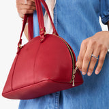 Cherry Small | Model holding a half circle crossbody bag with handles and removable crossbody strap 
