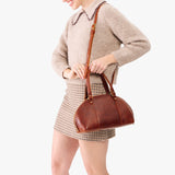 Nutmeg Small | Model holding a half circle crossbody bag with handles and removable crossbody strap 