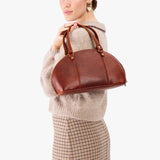 Nutmeg Small | Model holding a half circle crossbody bag with handles and removable crossbody strap 