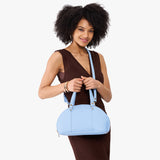 Skyway Small | Model holding a half circle crossbody bag with handles and removable crossbody strap