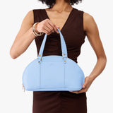 Skyway Small | Model holding a half circle crossbody bag with handles and removable crossbody strap
