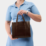 Chocolate Brown | Model wearing structured mid-size tote bag with overlapping panels and crossbody strap