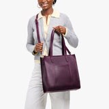 Larkspur North/South | Model holding structured large tote bag with overlapping panels and crossbody strap