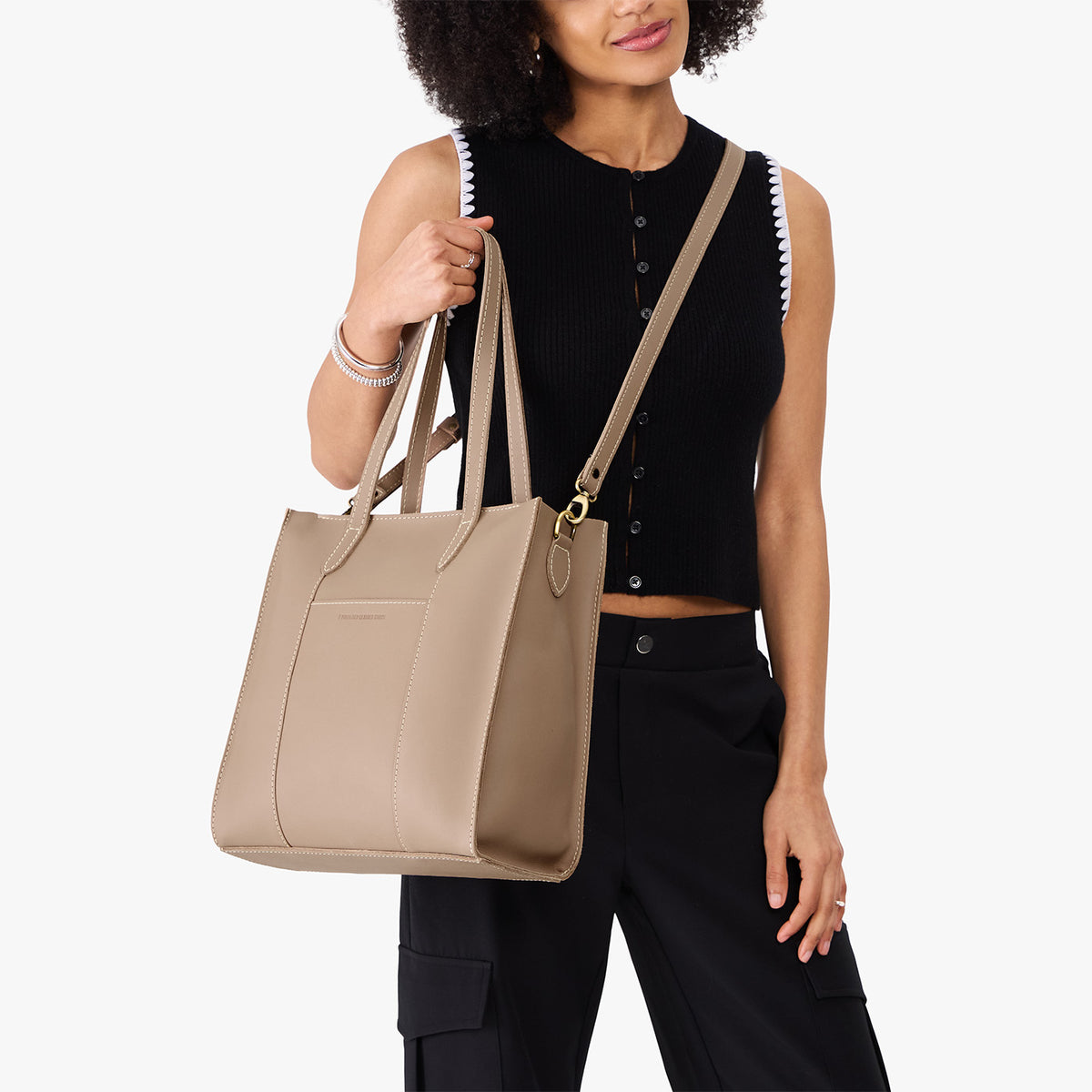Stone*North/South | Model holding structured wide tote bag with overlapping panels and crossbody strap