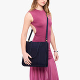 Velvet Blue North/South | Model holding structured large tote bag with overlapping panels and crossbody strap