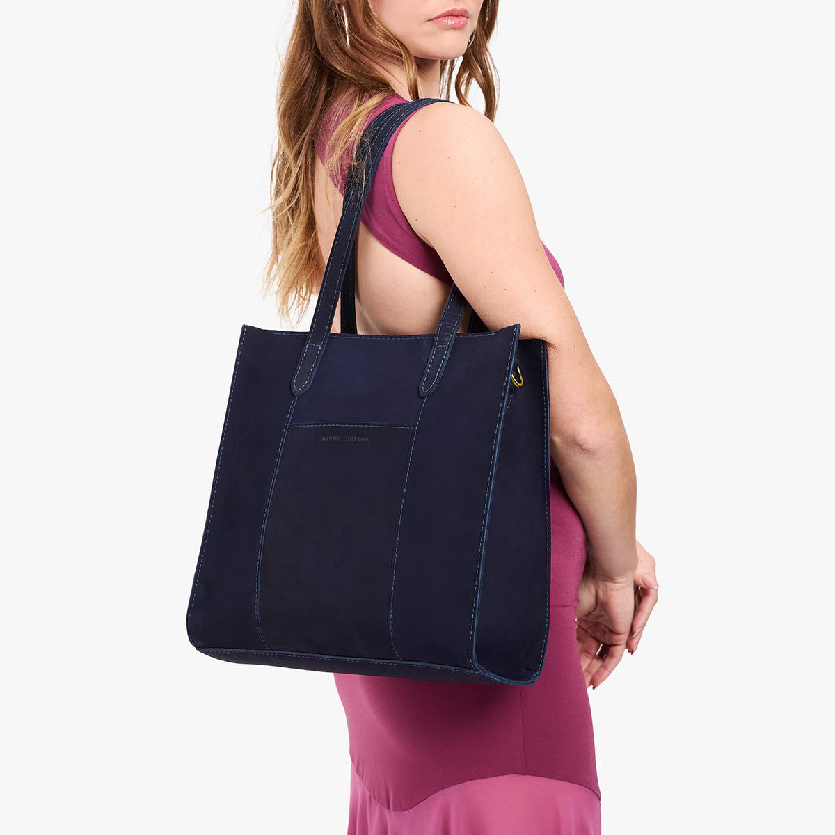 Velvet Blue*North/South | Model holding structured large tote bag with overlapping panels and crossbody strap