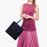 Velvet Blue North/South | Model holding structured large tote bag with overlapping panels and crossbody strap
