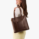 Chocolate Brown North/South | Model wearing structured large tote bag with overlapping panels and crossbody strap