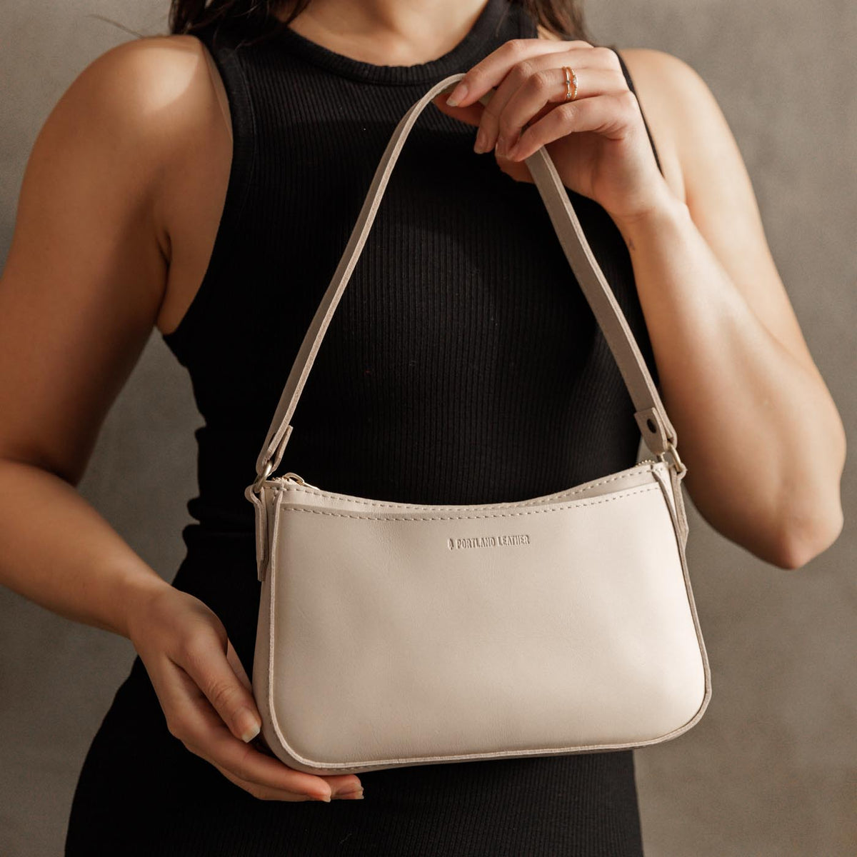 Bone*Small | Model holding petite bean shaped shoulder bag with a zipper closure