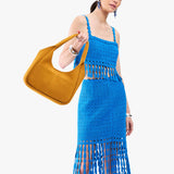 Dijon Medium | A model holding a u-shaped, flat-bottomed leather shoulder bag with two outside pockets