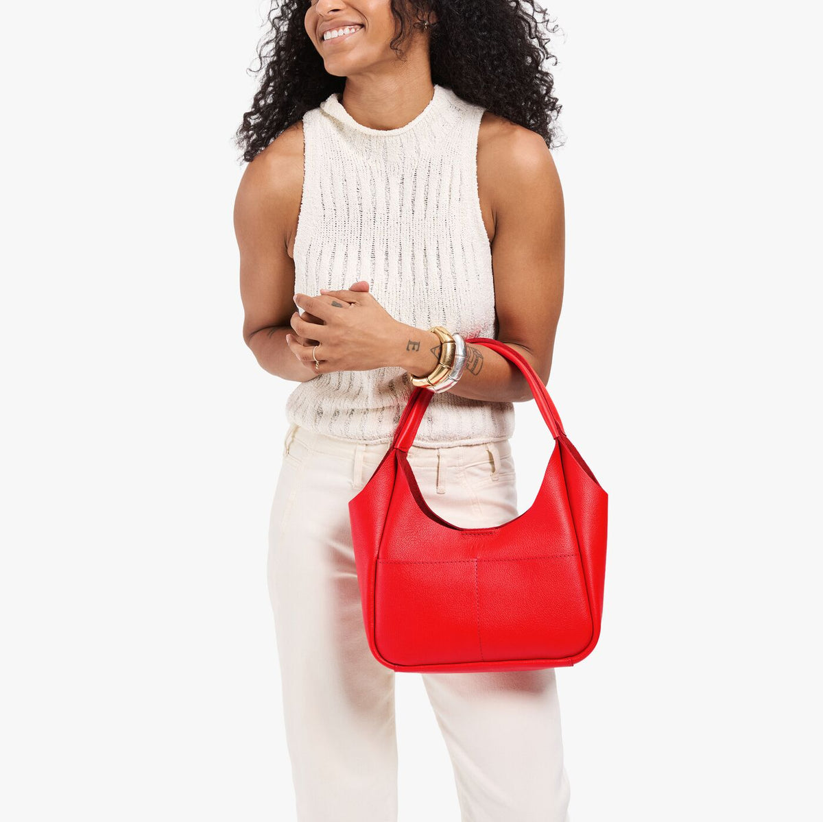 Candy*Medium | Model carrying a u-shaped, flat-bottomed leather shoulder bag with two outside pockets