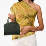 Evergreen Mini | Model holdng small leather tote bag with handles, adjustable crossbody strap, and one back pocket