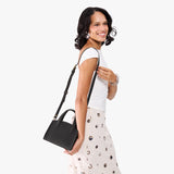 Full Moon Mini | Model carrying small leather tote bag with handles, adjustable crossbody strap, and one back pocket