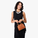 Honey Mini | Model carrying small leather tote bag with handles, adjustable crossbody strap, and one back pocket