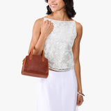 Nutmeg Mini | Model carrying small leather tote bag with handles, adjustable crossbody strap, and one back pocket