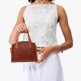 Nutmeg Mini | Model carrying small leather tote bag with handles, adjustable crossbody strap, and one back pocket