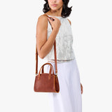 Nutmeg Mini | Model carrying small leather tote bag with handles, adjustable crossbody strap, and one back pocket