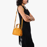 Sunshine Mini | Model carrying small leather tote bag with handles, adjustable crossbody strap, and one back pocket