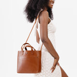 Honey Classic | Model holding crossbody tote bag with snap closure and front pocket