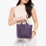 Empire Classic | Model holding crossbody tote bag with snap closure and front pocket