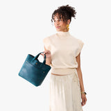 Westward Blue Classic | Model holding crossbody tote bag with snap closure and front pocket