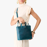 Westward Blue Classic | Model holding crossbody tote bag with snap closure and front pocket