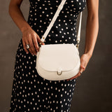 Bone Small | Model wearing a petite leather Crossbody with a flap and magnetic closure