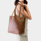 Asheville Medium Classic | Model holding a leather tote bag with riveted straps and exterior key loop