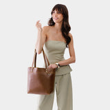 Asheville Medium Classic | Model holding a leather tote bag with riveted straps and exterior key loop