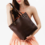 Coldbrew Medium Classic | Model holding leather tote bag with riveted straps and exterior key loop
