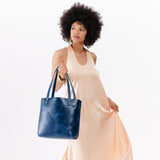 Cowboy Blue Medium Classic | Model holding leather tote bag with riveted straps and exterior key loop