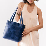 Cowboy Blue Medium Classic | Model holding leather tote bag with riveted straps and exterior key loop