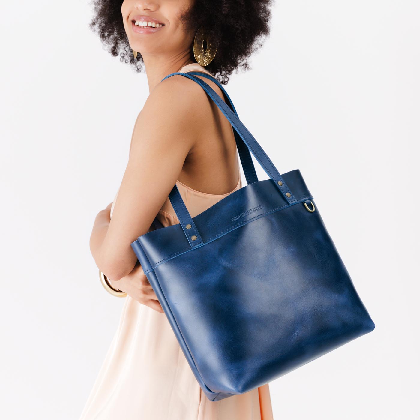 Cowboy Blue | Model wearing leather tote bag with riveted straps and exterior key loop