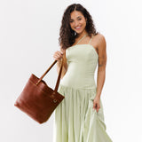 Nutmeg Medium Classic | Model holding leather tote bag with riveted straps and exterior key loop
