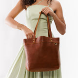Nutmeg Medium Classic | Model holding leather tote bag with riveted straps and exterior key loop