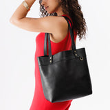 Pebbled--black Medium Classic | Model wearing leather tote bag with riveted straps and exterior key loop